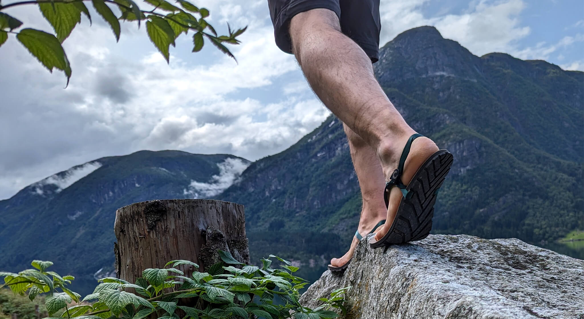 A_man_wearing_ZuZu_Groove_barefoot_sandals_featuring_an_antibacterial_vegan_leather_footbed_and_replaceable_Eucalyptus_color_recycled_strap