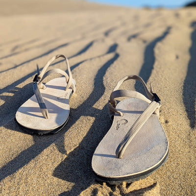 A_pair_of_ZuZu_Dune_barefoot_sandals_-_premium_water-repellent_leather_footbed_and_replaceable_recycled_desert_color_straps._Made_for_eco-friendly_barefoot_performance._Sandy_vibes