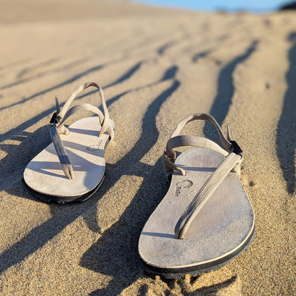 A_pair_of_ZuZu_Dune_barefoot_sandals_-_premium_water-repellent_leather_footbed_and_replaceable_recycled_desert_color_straps._Made_for_eco-friendly_barefoot_performance._Sandy_vibes