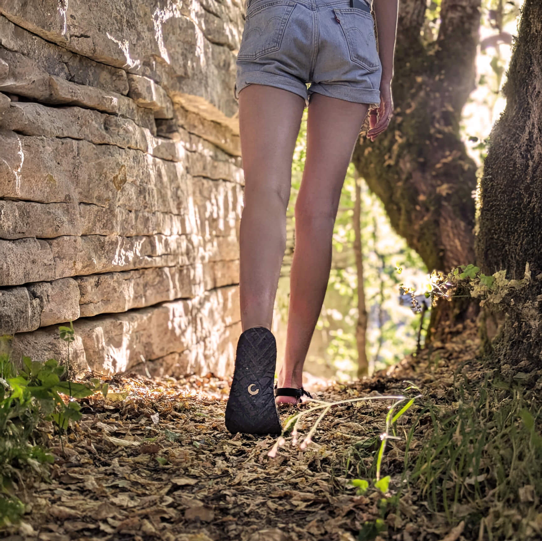 A_woman_walking_with_ZuZu_Drift_lightweight_eco-friendly_sandals_with_recycled_and_natural_sole_durable_canvas_footbed_and_recycled_straps._designed_for_all-day_comfort_and_minimalist