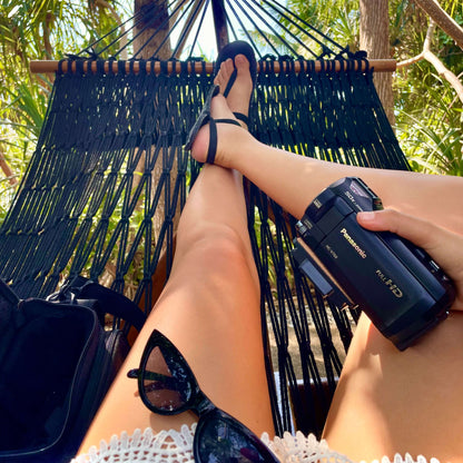 Woman in a hammock wearing ZuZu Flow barefoot sandals made from recycled car tires and black recycled straps combining eco-conscious materials with barefoot comfort for outdoor adventures.